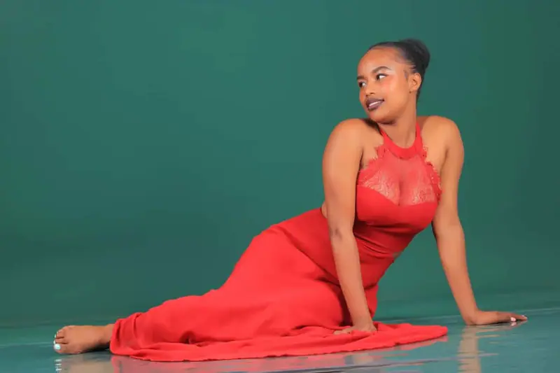Studio portrait of a woman in a red dress against a teal backdrop